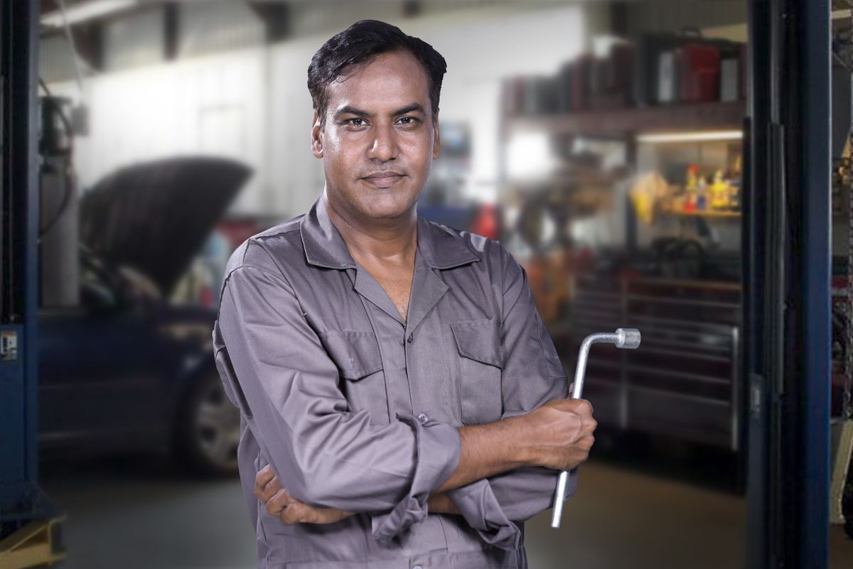 A mobile tyre fitter repairing a punctured car tyre with a wrench