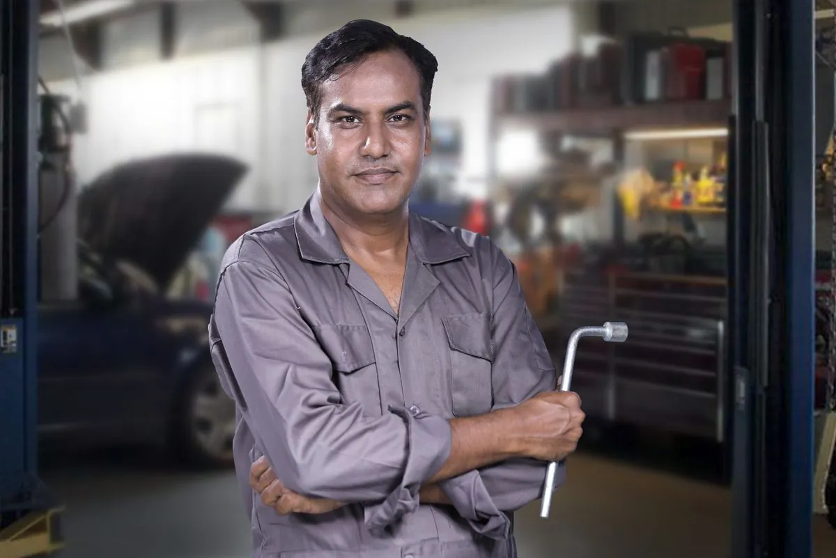 A mobile tyre fitter repairing a punctured car tyre with a wrench