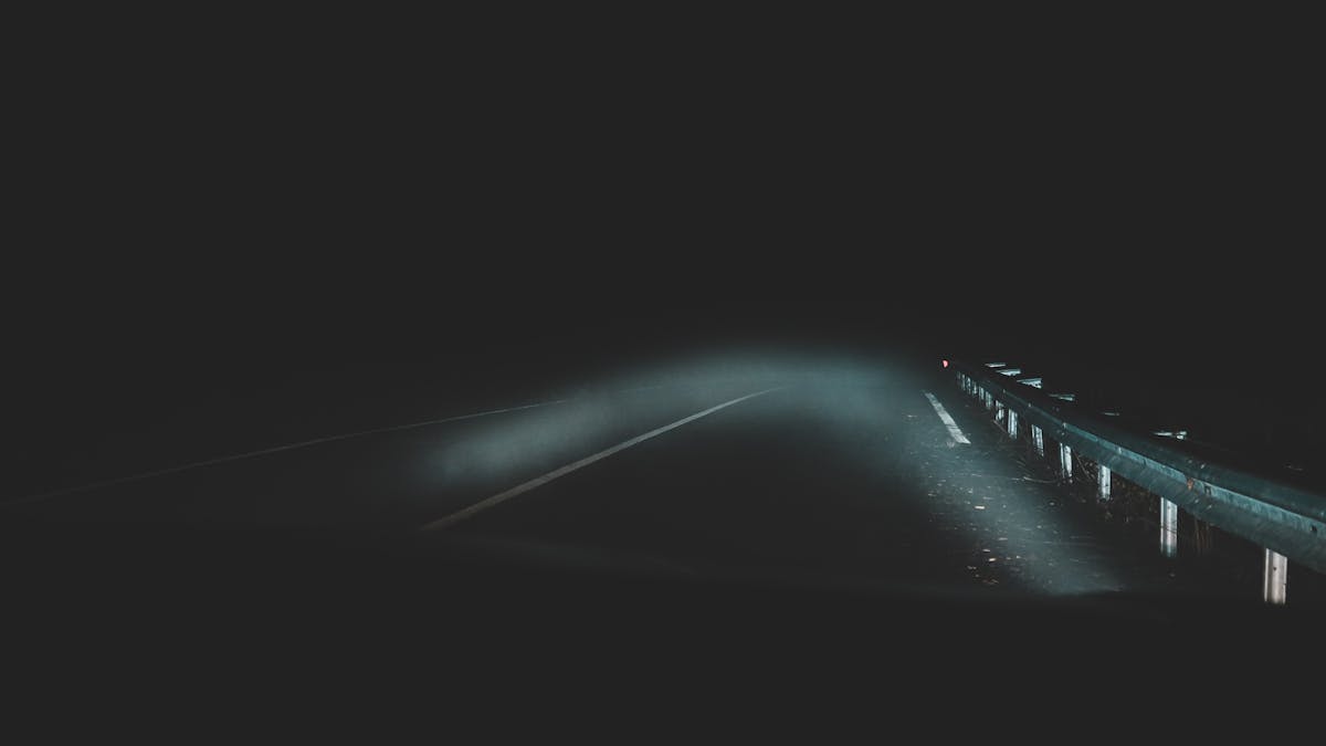A car driving at night on a dark road with headlights on
