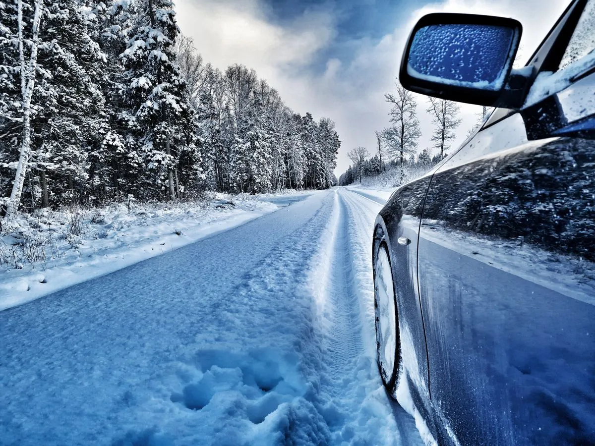 A car on a snowy winter road with tyres prepared for the season