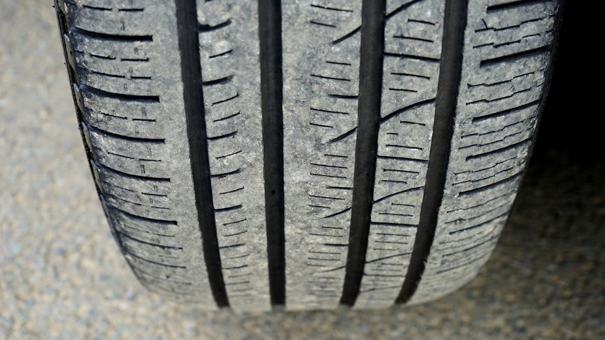 Close-up of a worn car tyre tread pattern showing the legal depth limit